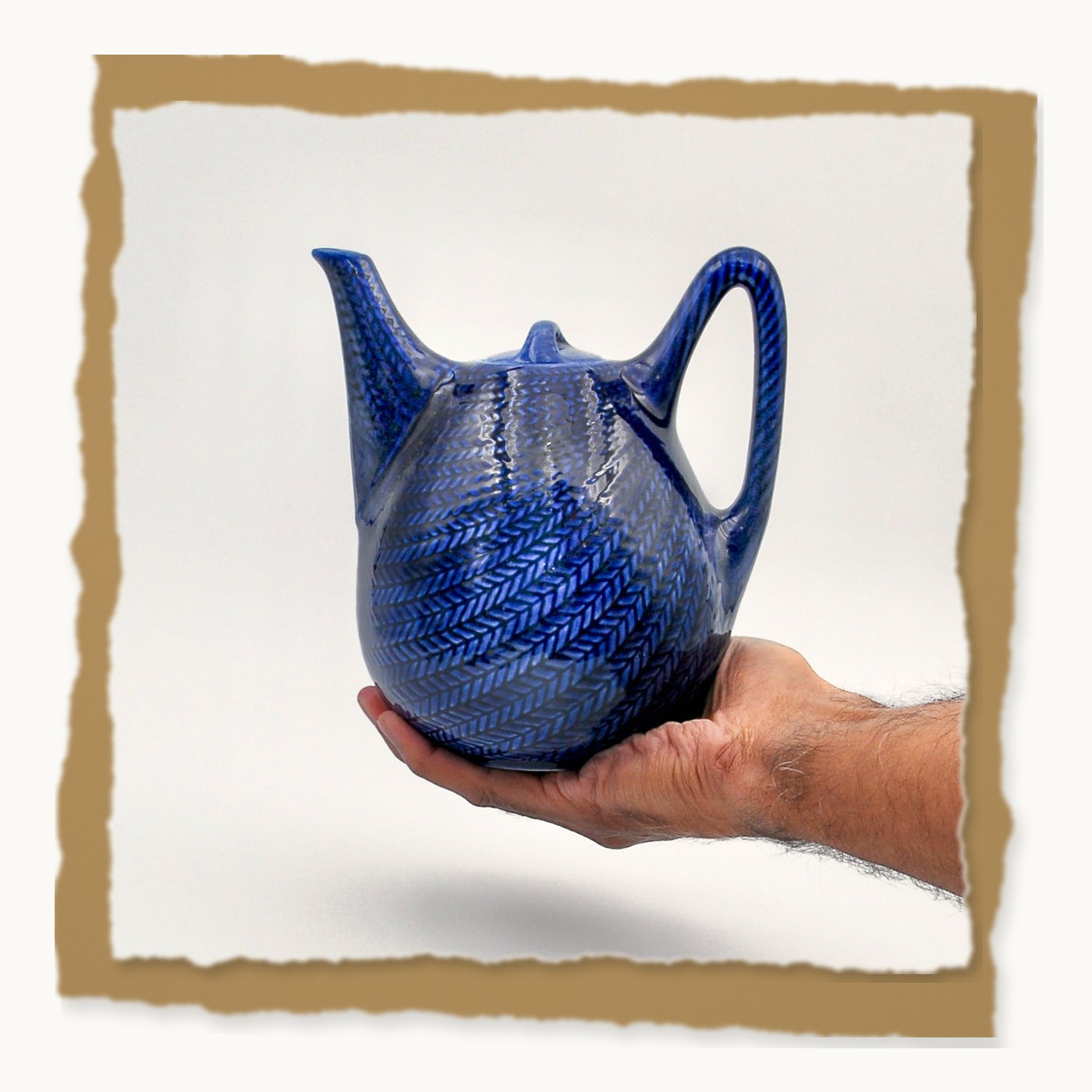 A hand cradling the blue Blå Eld teapot