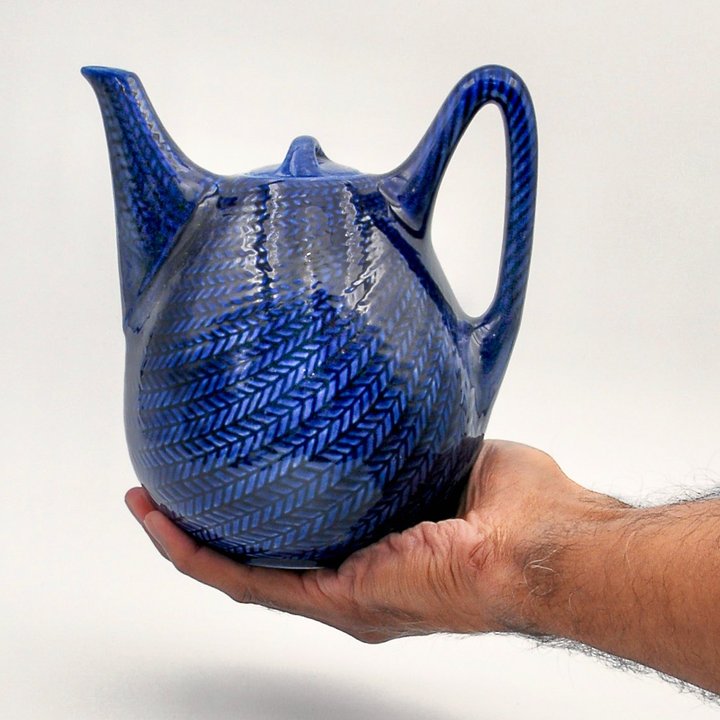 Hertha Bengtson's Blå Eld flintware teapot for Rörstrand, cradled in a hand